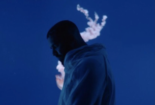 A man stands silhouetted against a blue background