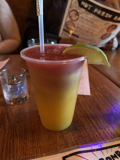 A plastic cup filled with orange and red sake slushy on a table