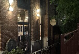 A night image of glass doors on the side of brick building with circular signs for The Southern.