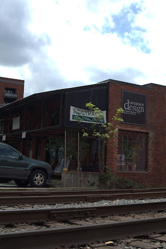 A brick building, known as the Downtown Design Center, sits across from train tracks.