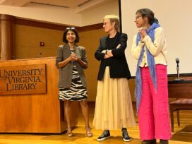 Three women stand next to a podium labeled with the UVA library logo.