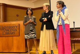 Three women stand next to a podium labeled with the UVA library logo.