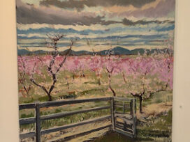 An oil painting of peach blossoms on canvas hangs on a wall.