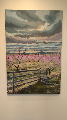 An oil painting of peach blossoms on canvas hangs on a wall.