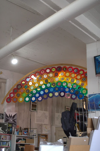 A display of translucent vinyl records is set up to look like a rainbow inside of a music store.