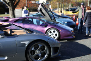 Three supercars are parked side by side on main display in a parking lot. Left to Right: Grey Koenigsegg CCXR, Purple Lamborghini Diablo SE30, Powder Blue Lexus LFA.