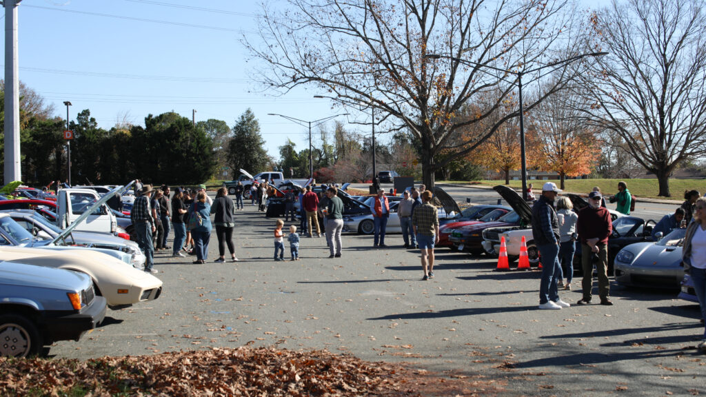 Two rows of the Charlottesville High School Fall Charity Car Show, with spectators viewing the attendants’ cars.