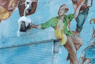 A mural represents a man pouring a frosty beer from a keg on a painted barrel.