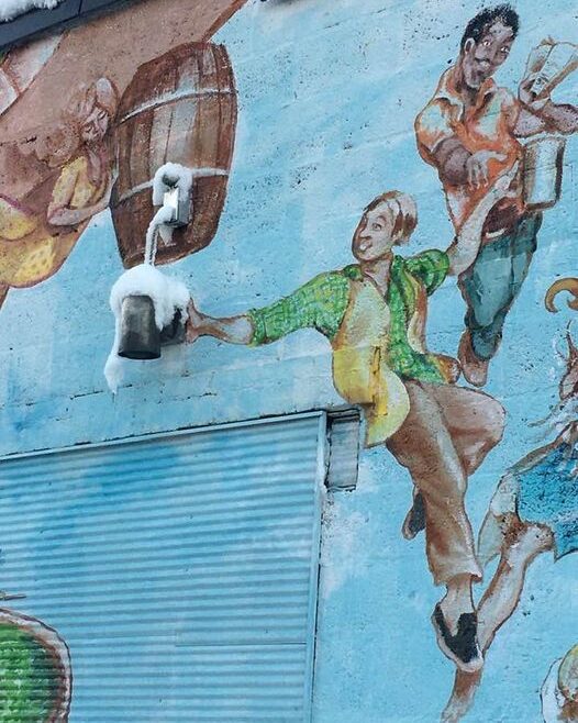 A mural represents a man pouring a frosty beer from a keg on a painted barrel.