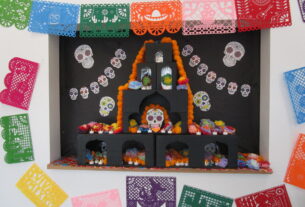 A decorative ofrenda with stencil cutouts made of paper surrounding it.