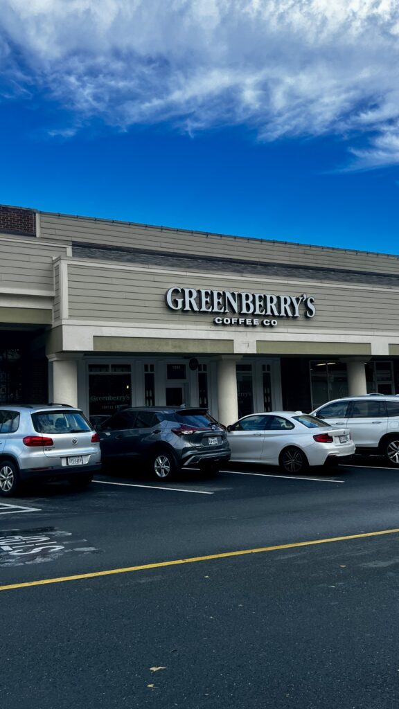 The storefront of Greenberry's Coffee, with multiple cars parked in front.