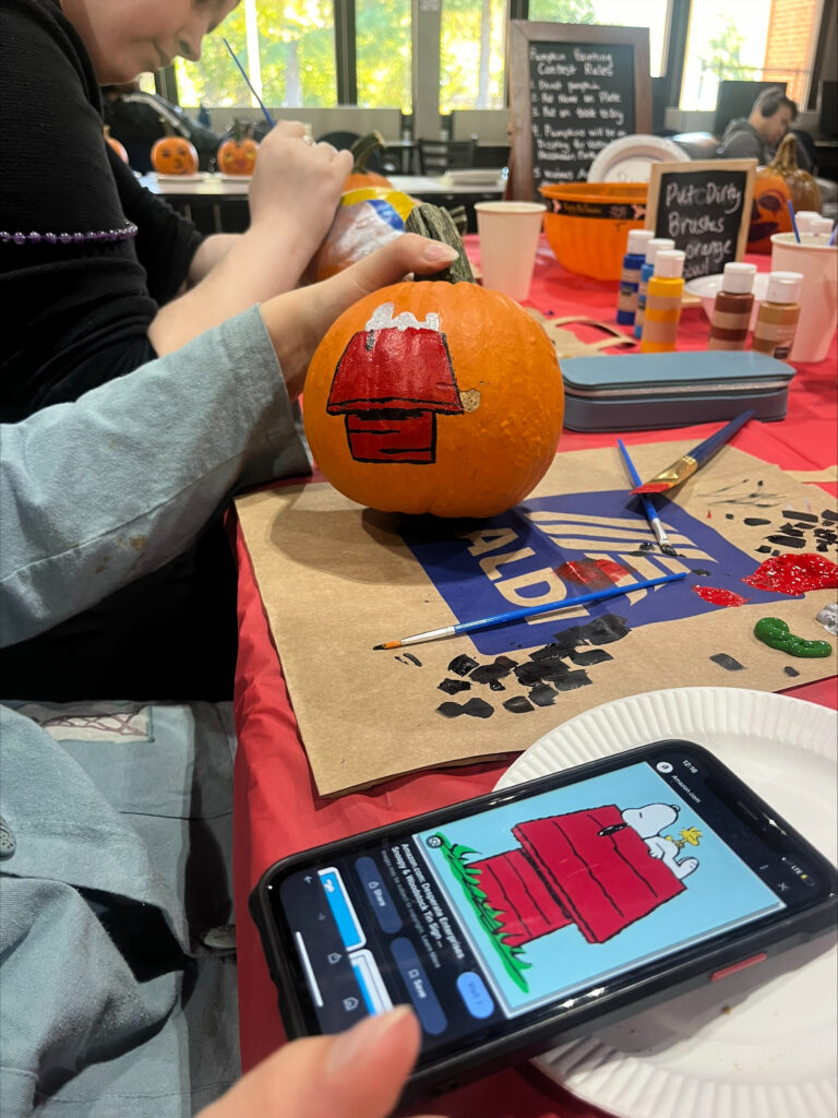 Students paint Snoopy sleeping on his doghouse on a small pumpkin.