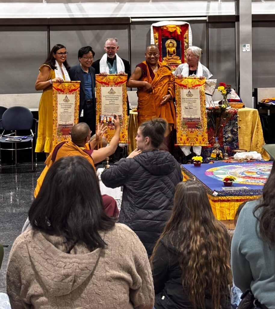 Teachers and monks stand before a crowd of students as the sand mandala is finished.