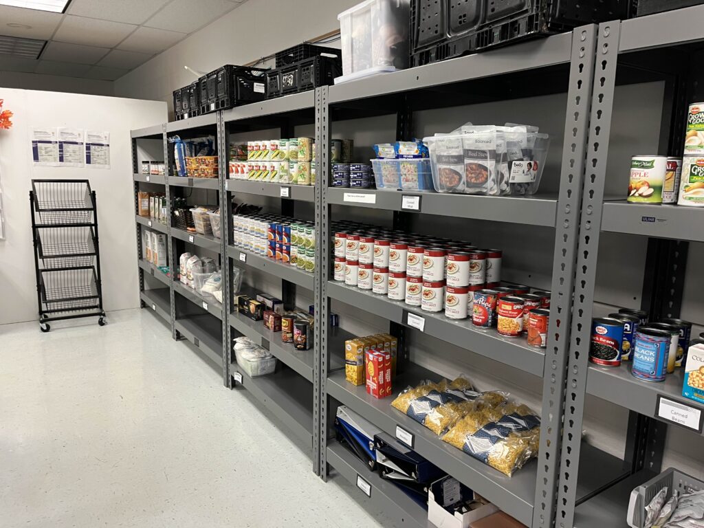 Canned food and pasta sits on grey shelves in the Student Resource Center.