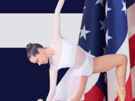 A young ballerina in white posing with an American flag behind her.