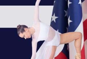 A young ballerina in white posing with an American flag behind her.