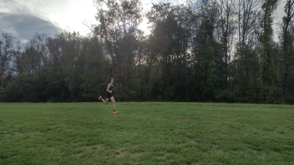 A high school student wearing black runs in a field