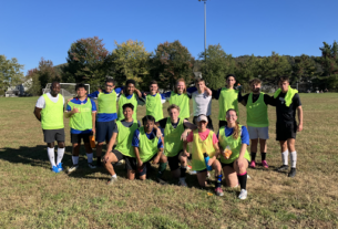 A group of PVCC students in neon green jerseys huddle up for a group photo.