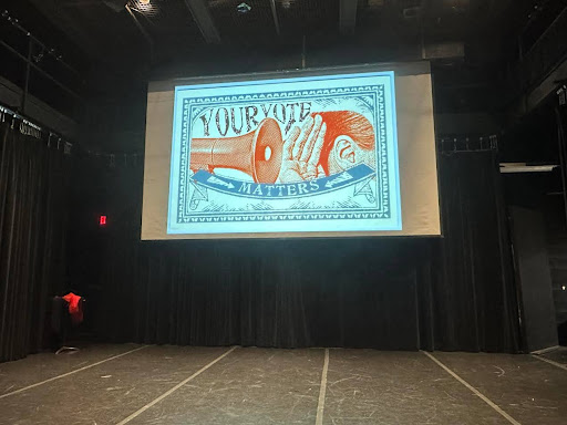 PVCC's Black Box Theater with a projection of a sign which reads "Your Vote Matters" with the graphic of a megaphone pointed at a cupped hand next to an ear.